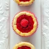 An overhead shot of three Mini Raspberry Cheesecake Muffins on a white plate