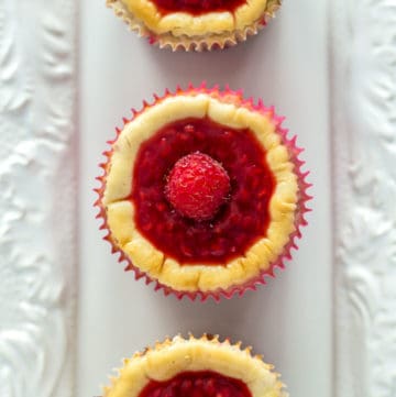An overhead shot of three Raspberry Mini Cheesecake Muffins on a white plate