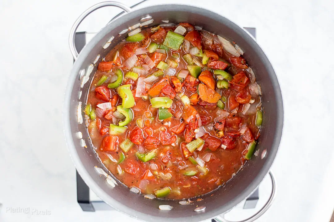 Process shot of adding canned diced tomatoes to pot