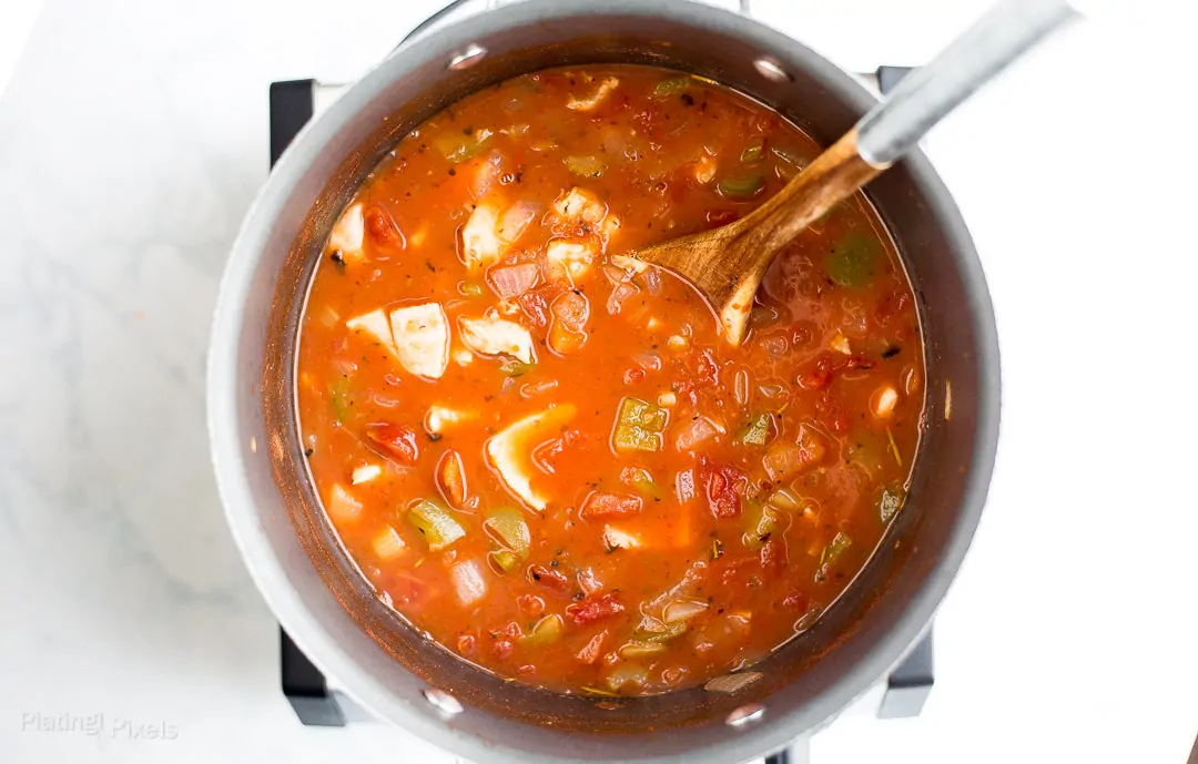 Process shot of fish soup simmering in a pot