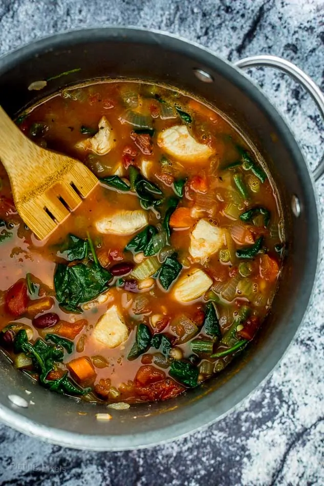 One Pot Chicken Minestrone Soup in a large pot with a wooden spoon