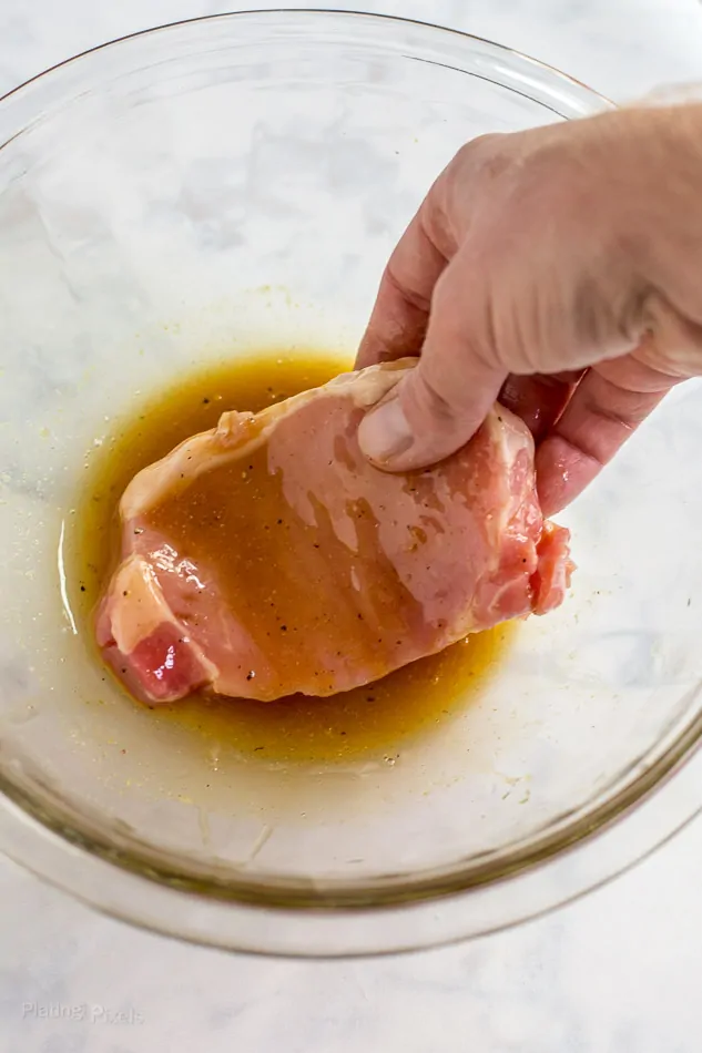 Process shot of dredging pork chops in a honey mustard sauce