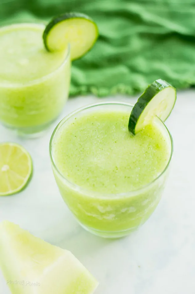 Cucumber Melon Cocktail Slushie in a glass next to melon slice