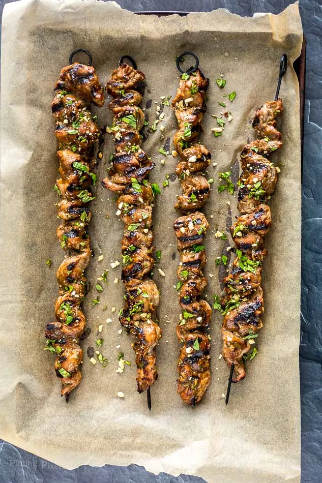 Grilled Pork Satay Skewers on a sheet of parchment paper