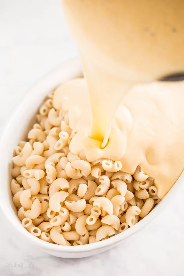 Pouring cheese sauce over Gluten-Free Mac and Cheese 