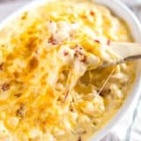 Wooden spoon scooping Gluten-Free Mac and Cheese from a casserole dish