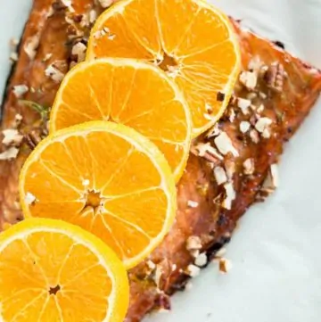 Close up of Maple Glazed Sheet Pan Salmon on baking sheet topped with orange slices
