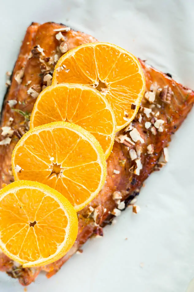 Close-up of roasted Maple Glazed Sheet Pan Salmon topped with sliced oranges and pecans pieces
