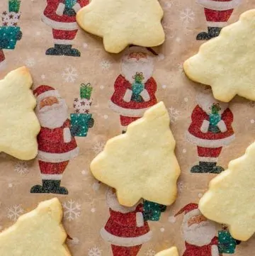Baked Sugar Cookies over a Santa Claus decorated paper backdrop