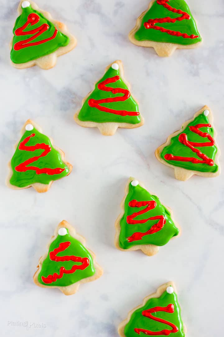 Lots of Decorated Christmas Tree Cookies with Royal Icing arranged a white background
