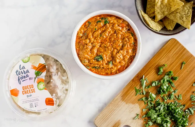 Overhead shot of Slow Cooker Chorizo Queso Dip in a bowl next to package or La Terra Fina dip