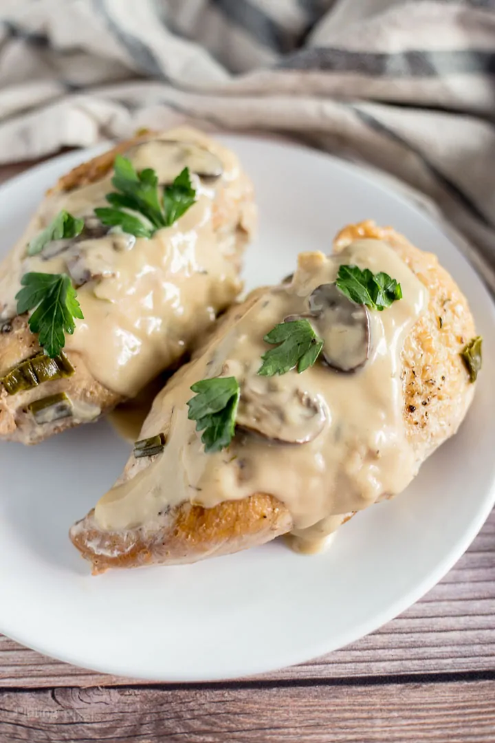 Close up of two slow cooked turkey breasts smothered in marsala sauce on a plate on table