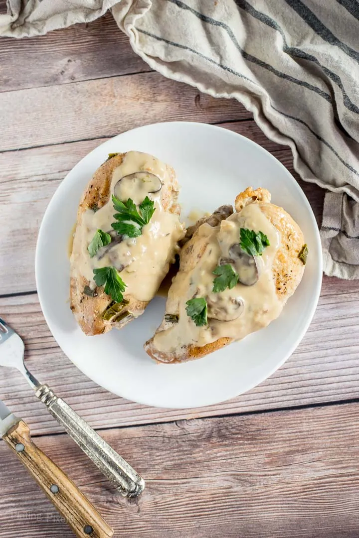 Overhead shot of wo slow cooked turkey breasts smothered in marsala sauce on a plate on table