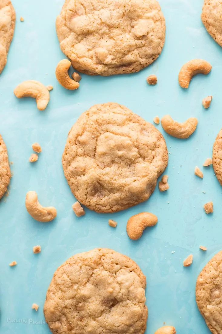 Chewy Cashew Toffee Cookies baking on a teal baking sheet