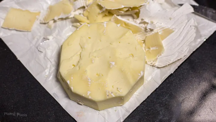 Brie cheese wheel with rind cut off on a kitchen counter