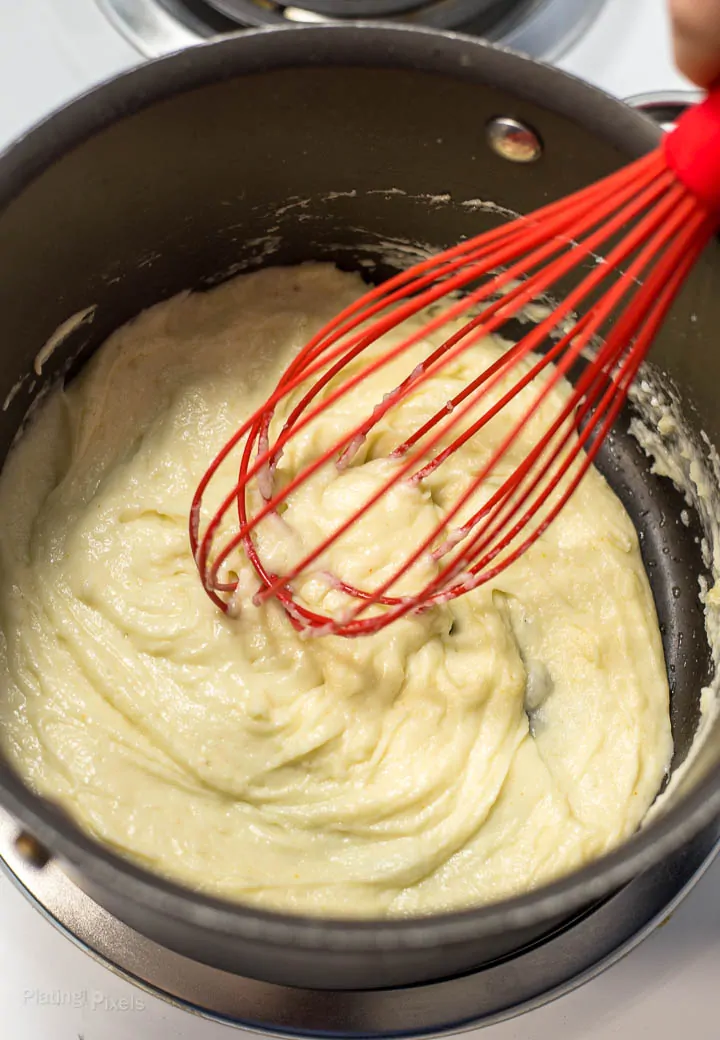 Process shot of stirring together cheese and roux in saucepan on stove to make an Easy Cheese Souffle