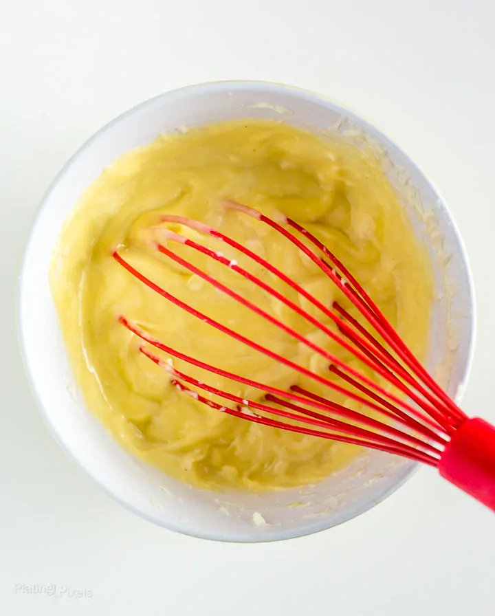 Process shot of stirring egg yolks into cheese mixture in a bowl to make Easy Cheese Souffle with Brie Cheese
