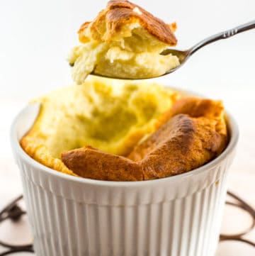 Scoop of Easy Cheese Souffle with Brie Cheese on a spoon hovering over ramekin dish