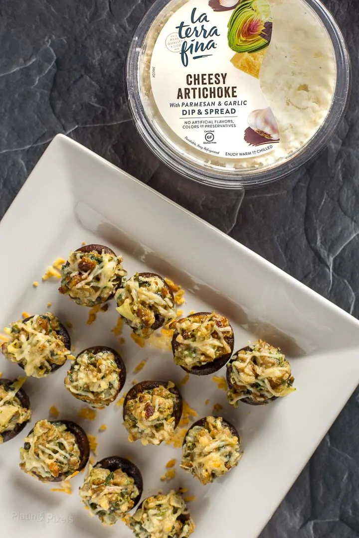 Overhead shot of Sausage Stuffed Mushrooms on a plate next to La Terra Fina dip