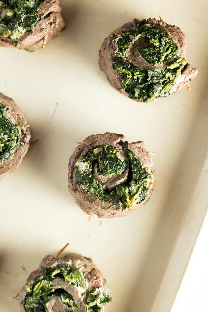 Creamy Spinach Stuffed Flank Steak Pinwheels just broiled on a baking sheet