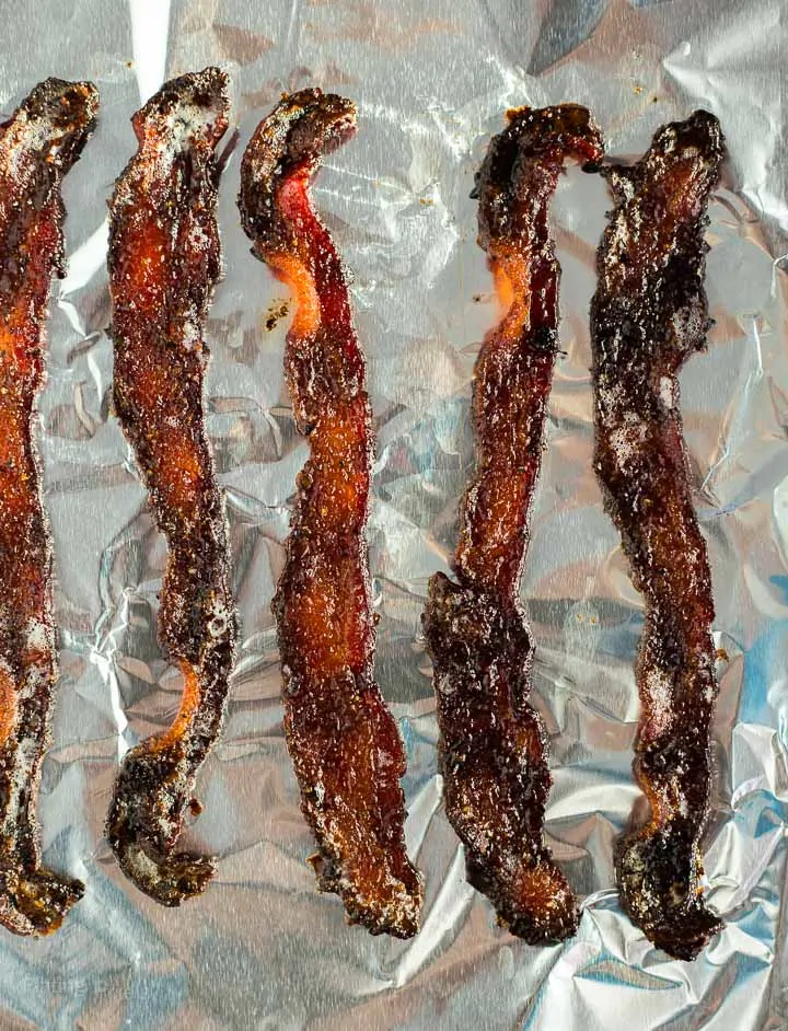 Cooked candied bacon pieces on a bacon sheet