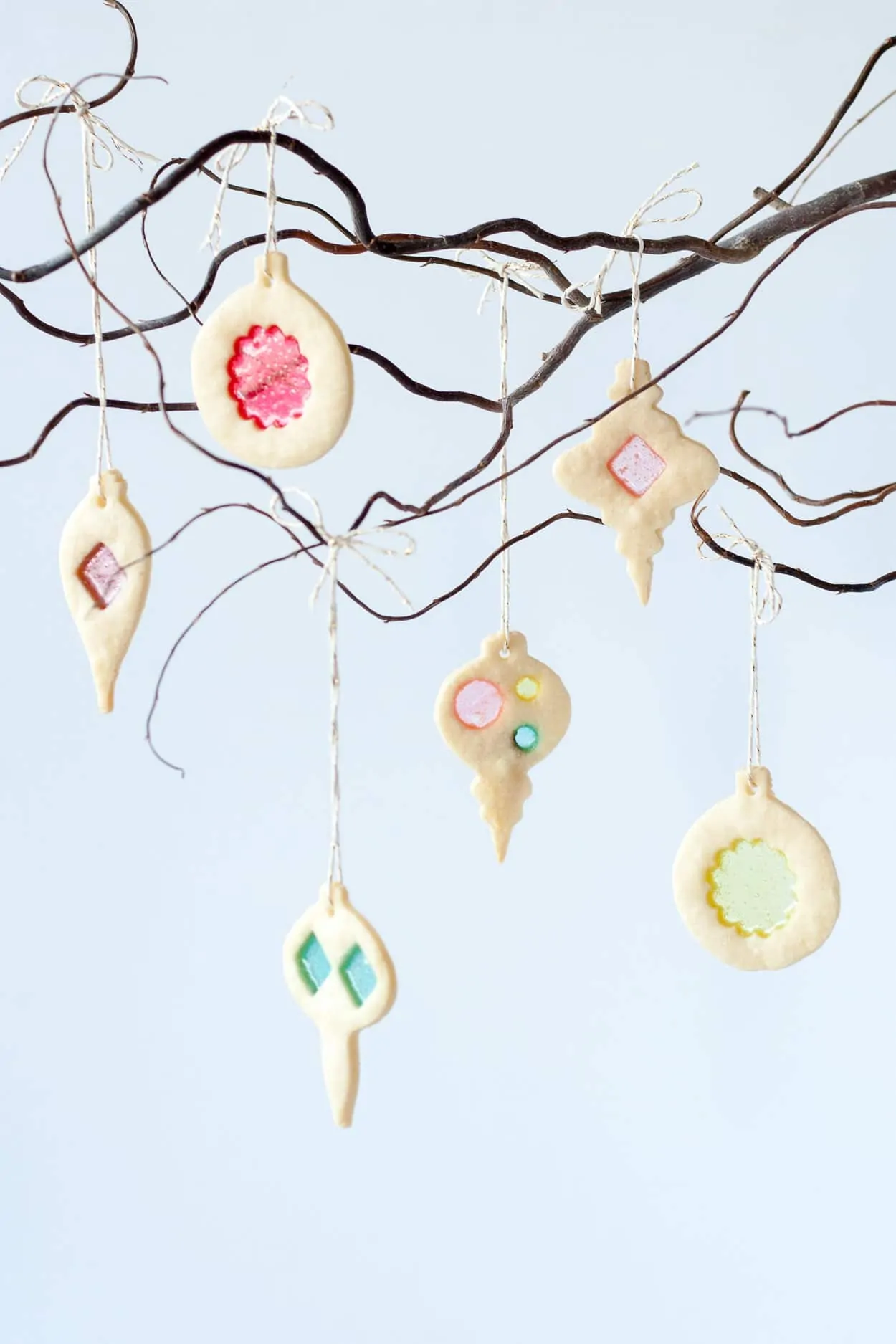 Stained glass Christmas decorated cookies hanging from branch