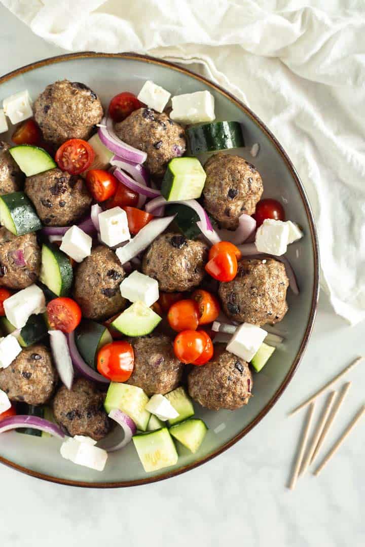 Overhead shot of a plate of Greek Baked Meatballs and chopped veggies