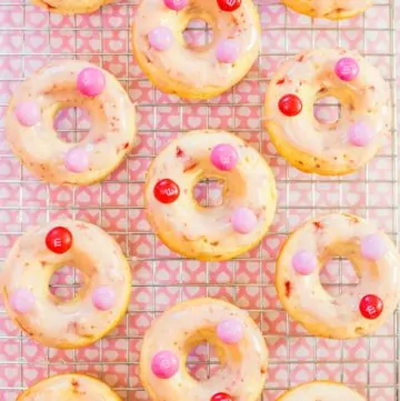 An overhead shot of Strawberry Glazed Baked Doughnuts on a cooling rack topped with pink M&M's