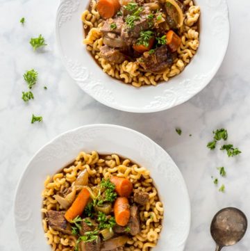 Two bowls of prepared Slow Cooker Beef Stew with root vegetables on a marble table