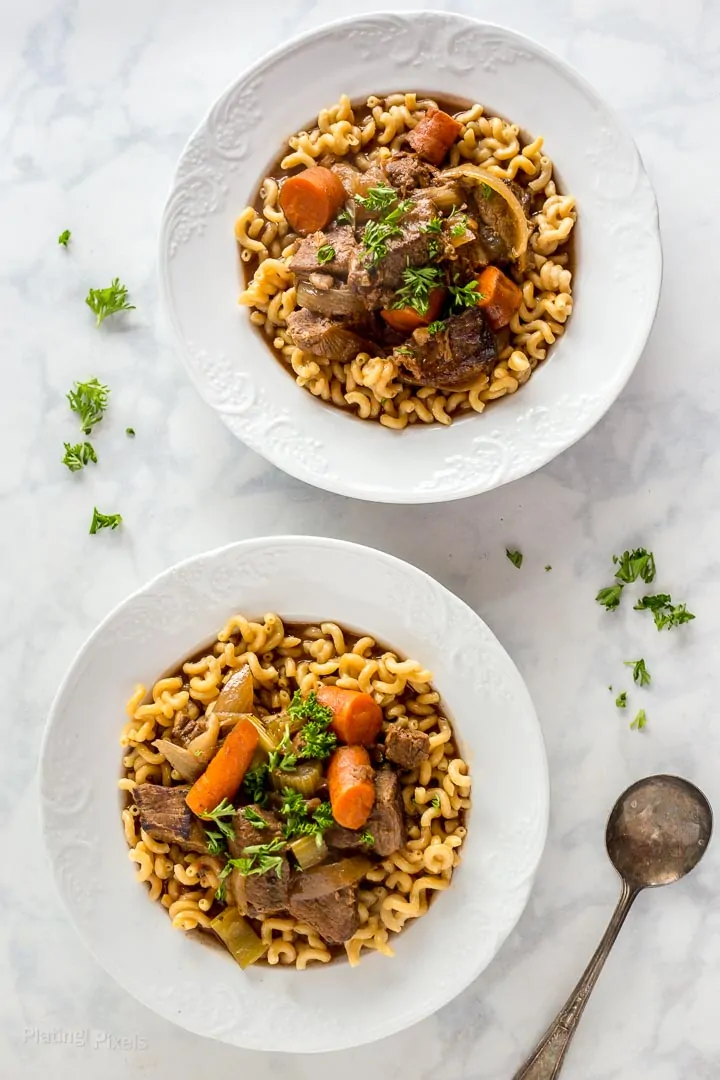 Two bowls of prepared Slow Cooker Beef Stew with root vegetables on a marble table