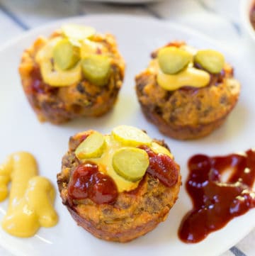 Mini Cheeseburger Muffins on a plate with pickles and ketchup