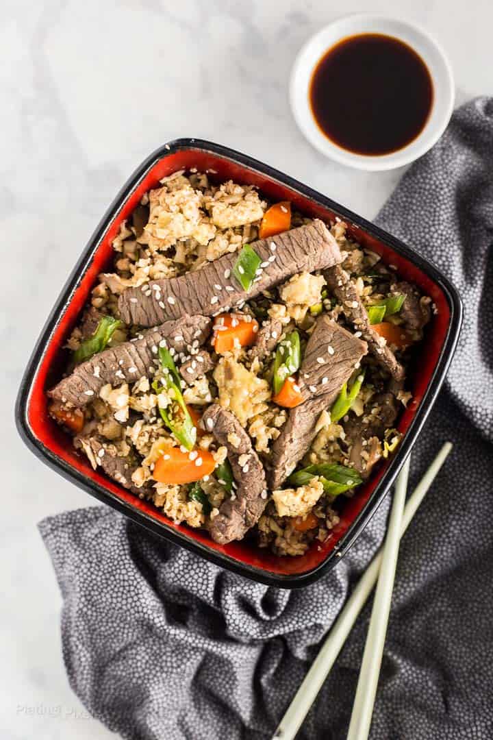 Overhead shot of Keto Beef Fried Rice in a bowl with chopsticks next to it