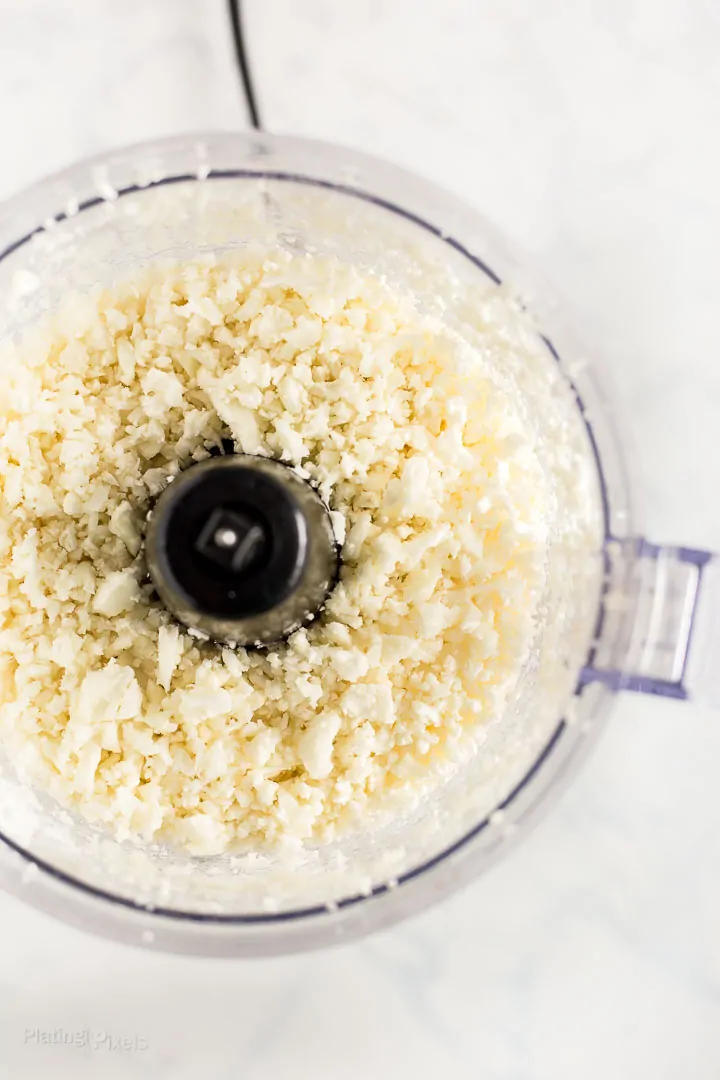 Process shot of pulsing cauliflower in a food processor to make cauliflower rice