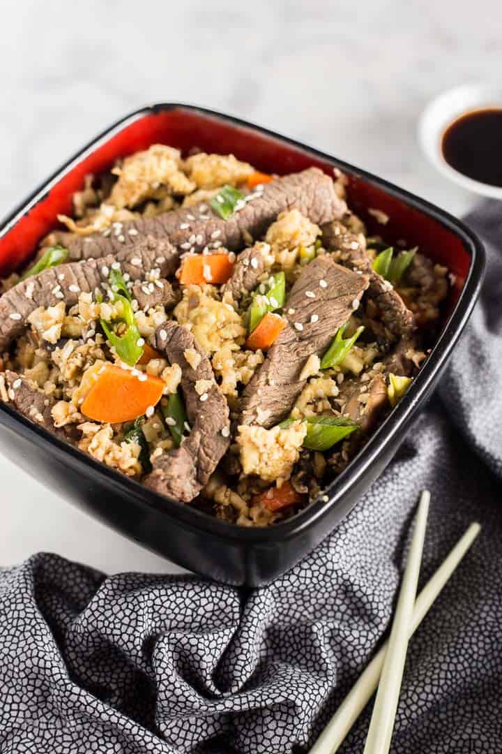 Close up of Keto Beef Fried Rice in a bowl with chopsticks next to it