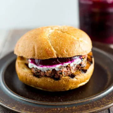 Prepared Grilled Veggie Burger on a plate with jar of pickled beets in the background