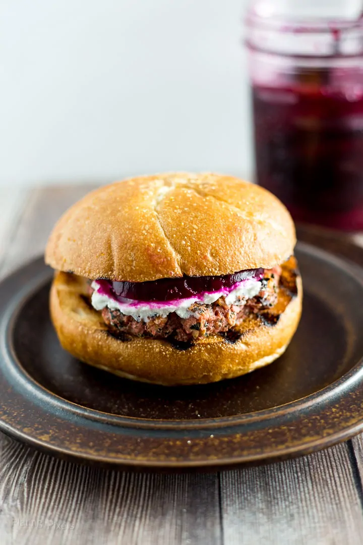 Prepared Grilled Veggie Burger on a plate with jar of pickled beets in the background