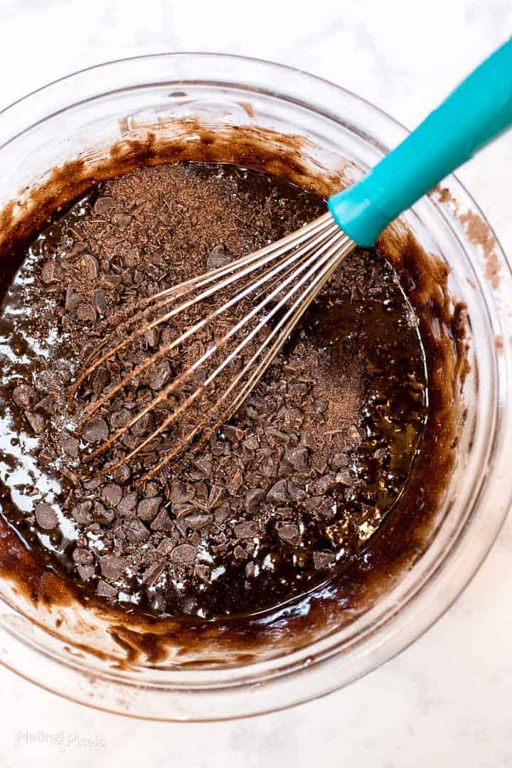 Process shot of stirring chocolate chips into brownie batter