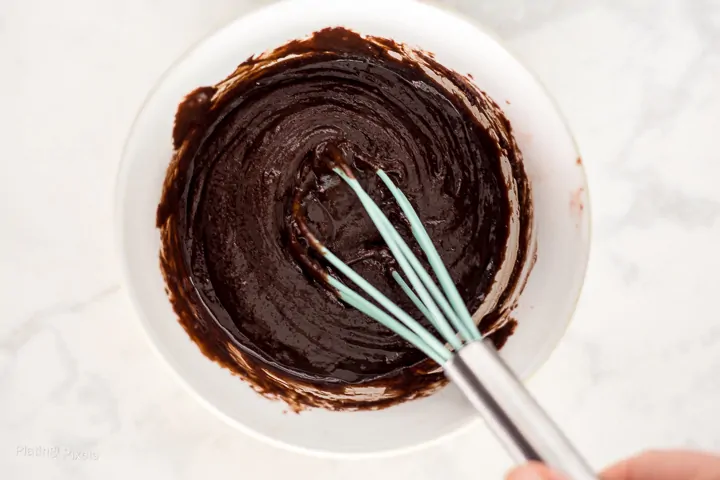 Process shot of mixing together brownie batter in a bowl