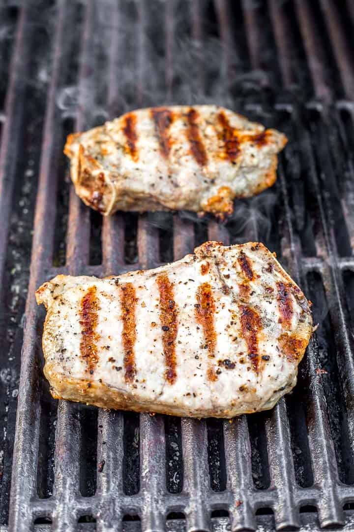 Two bone in pork chops on grill with sear marks