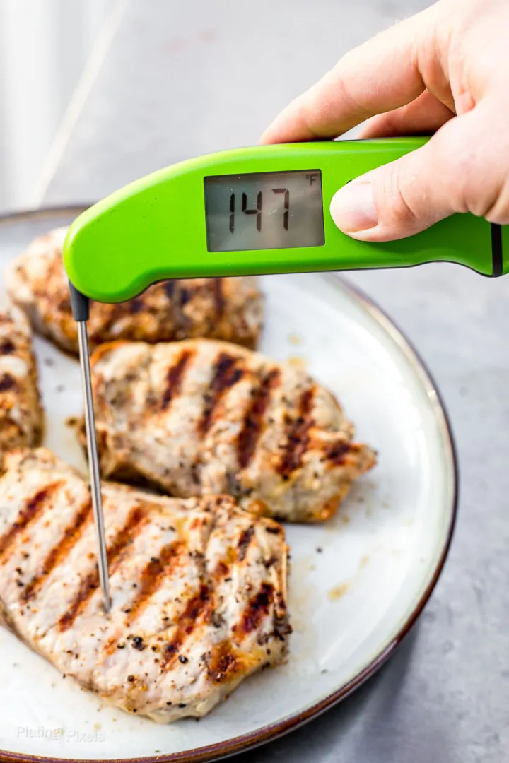 Checking temperature of grilled pork chops with a digital thermometer (temp is 147 degrees)