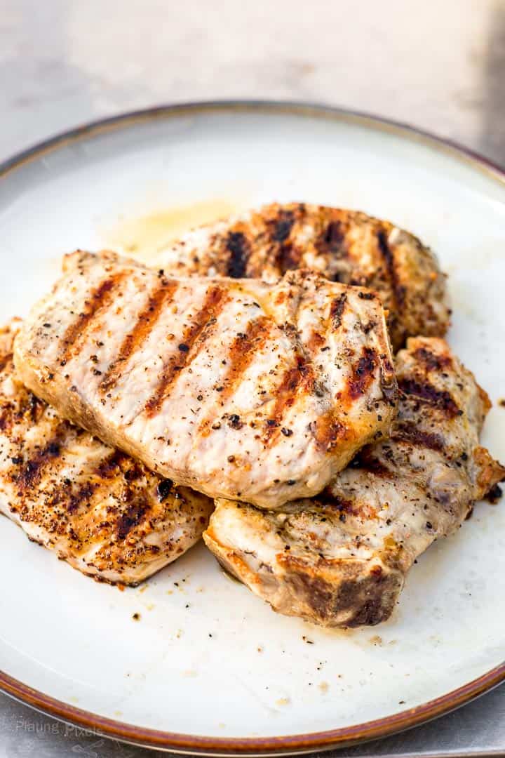 Pile of perfectly grilled pork chops resting on a plate