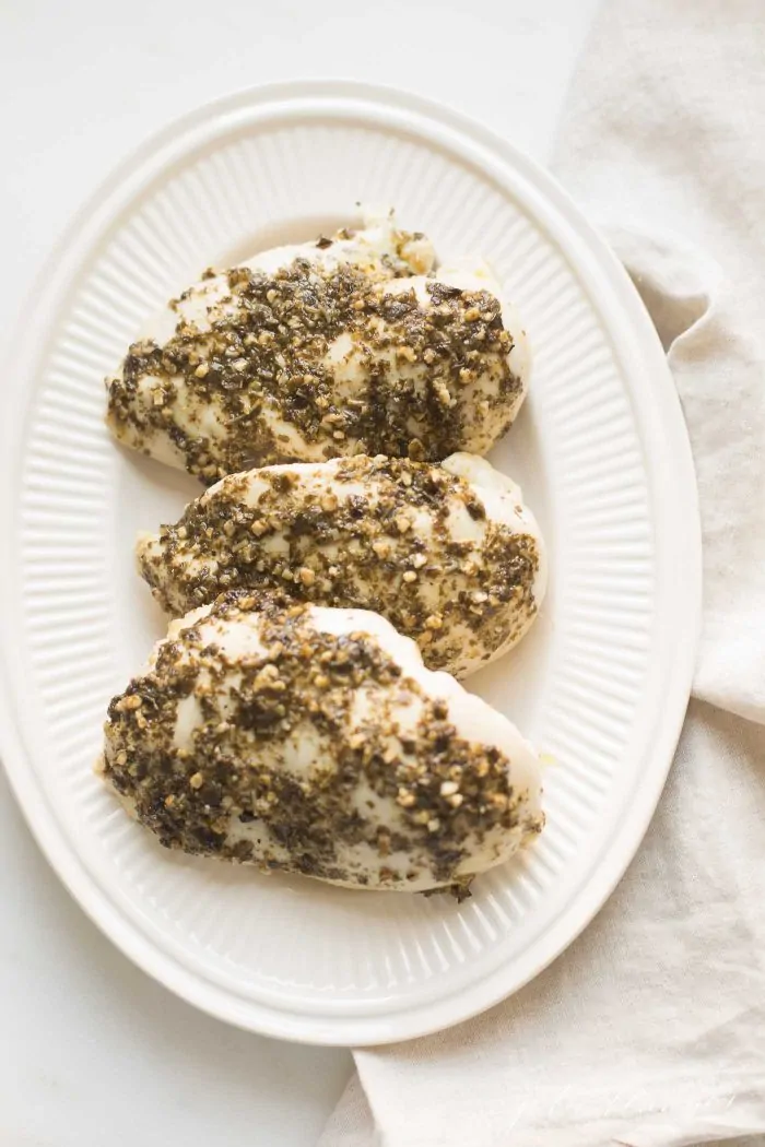 Three baked chicken breasts covered with pesto