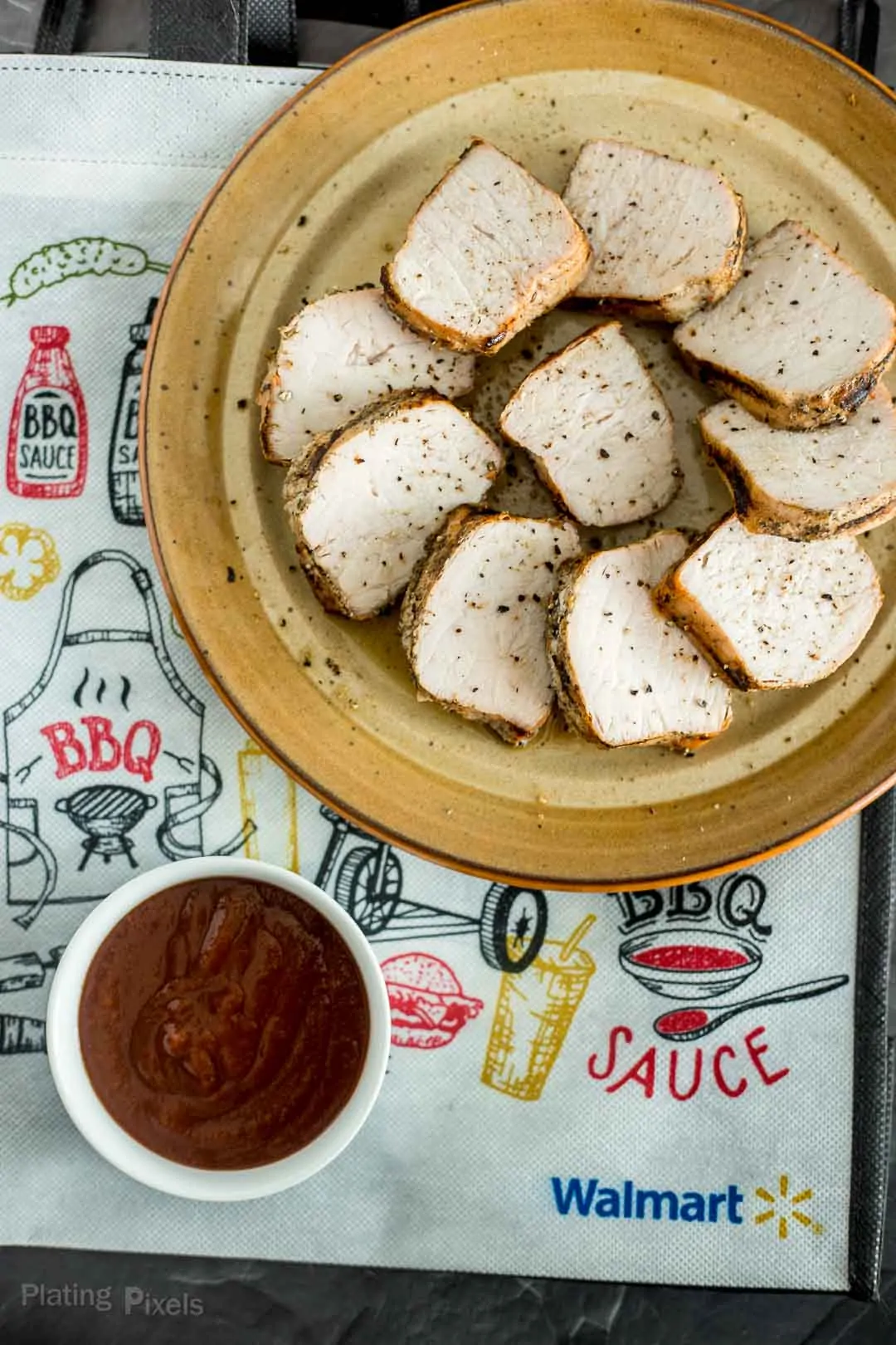 Grilled pork tenderloin slices next to BBQ sauce for dipping