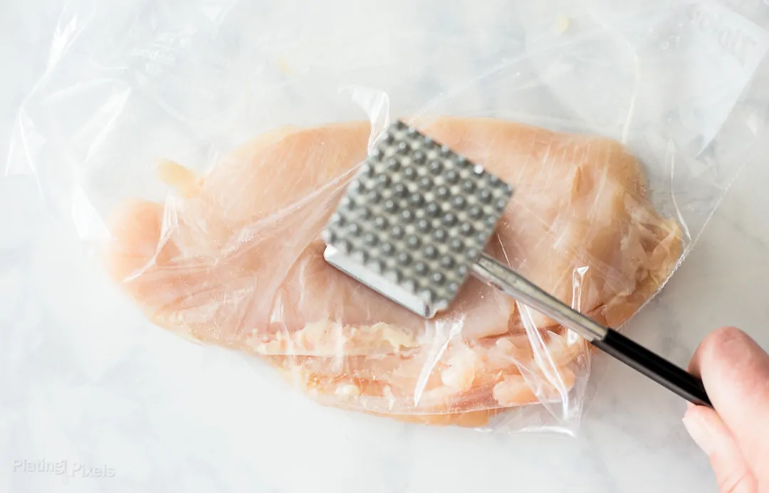 Process shot of pounding a chicken breast with a meat mallet