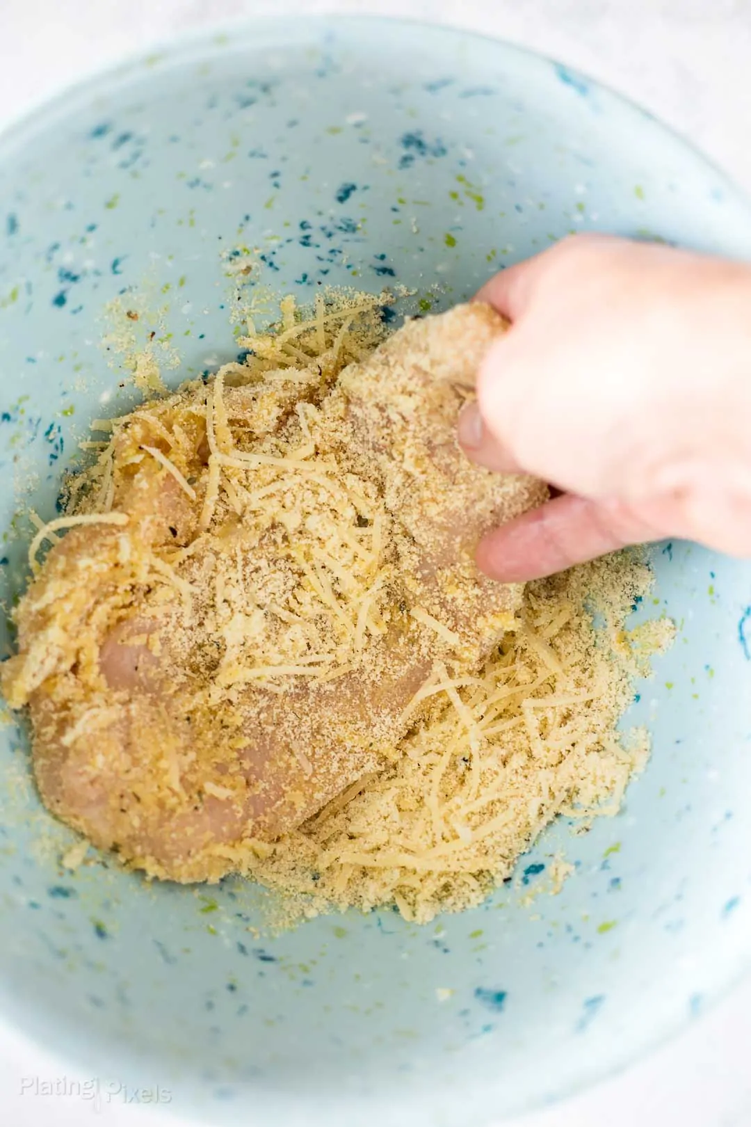 Process shot of dipping chicken breast in keto breading mixture