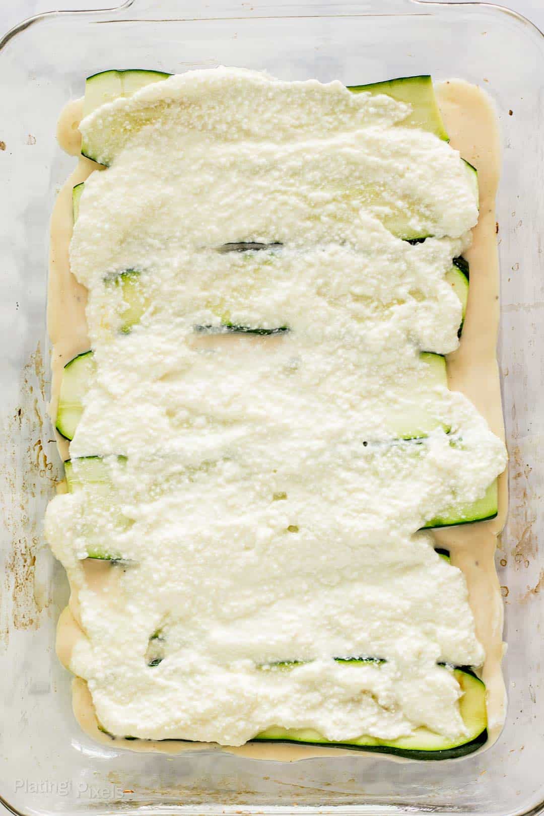 Process shot - adding ricotta mixture to make zucchini lasagna