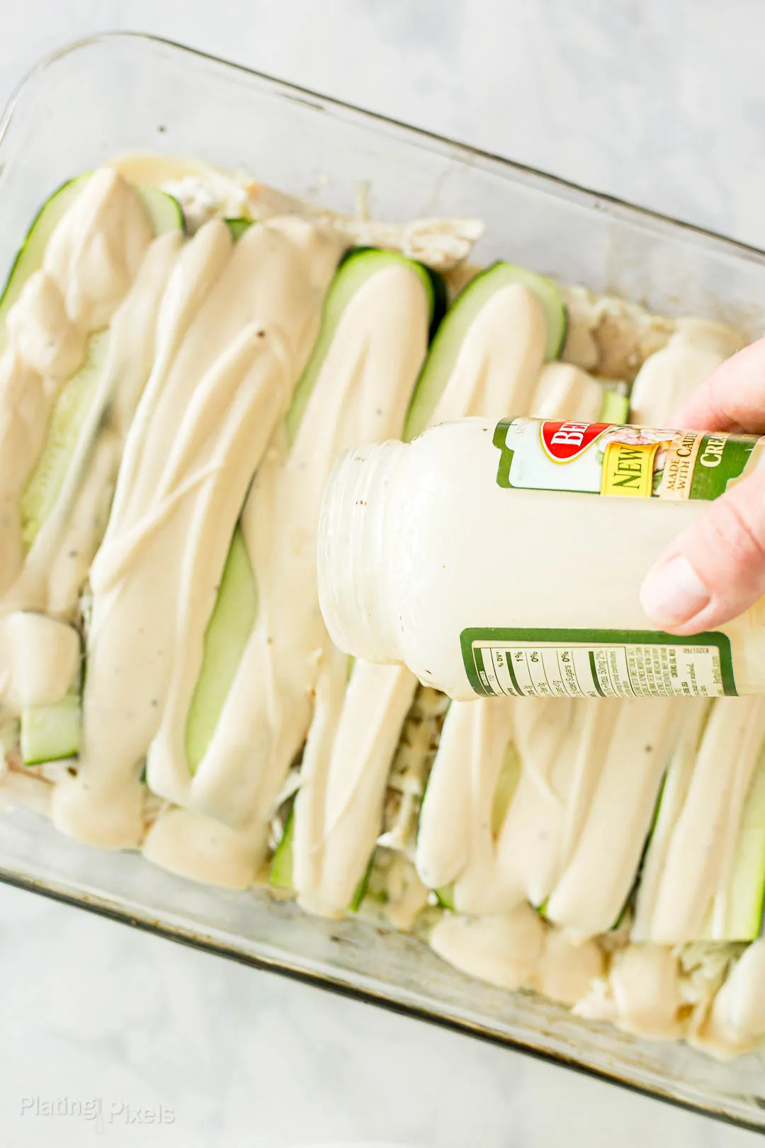 Process shot - pouring alfredo sauce to make a Zucchini Lasagna