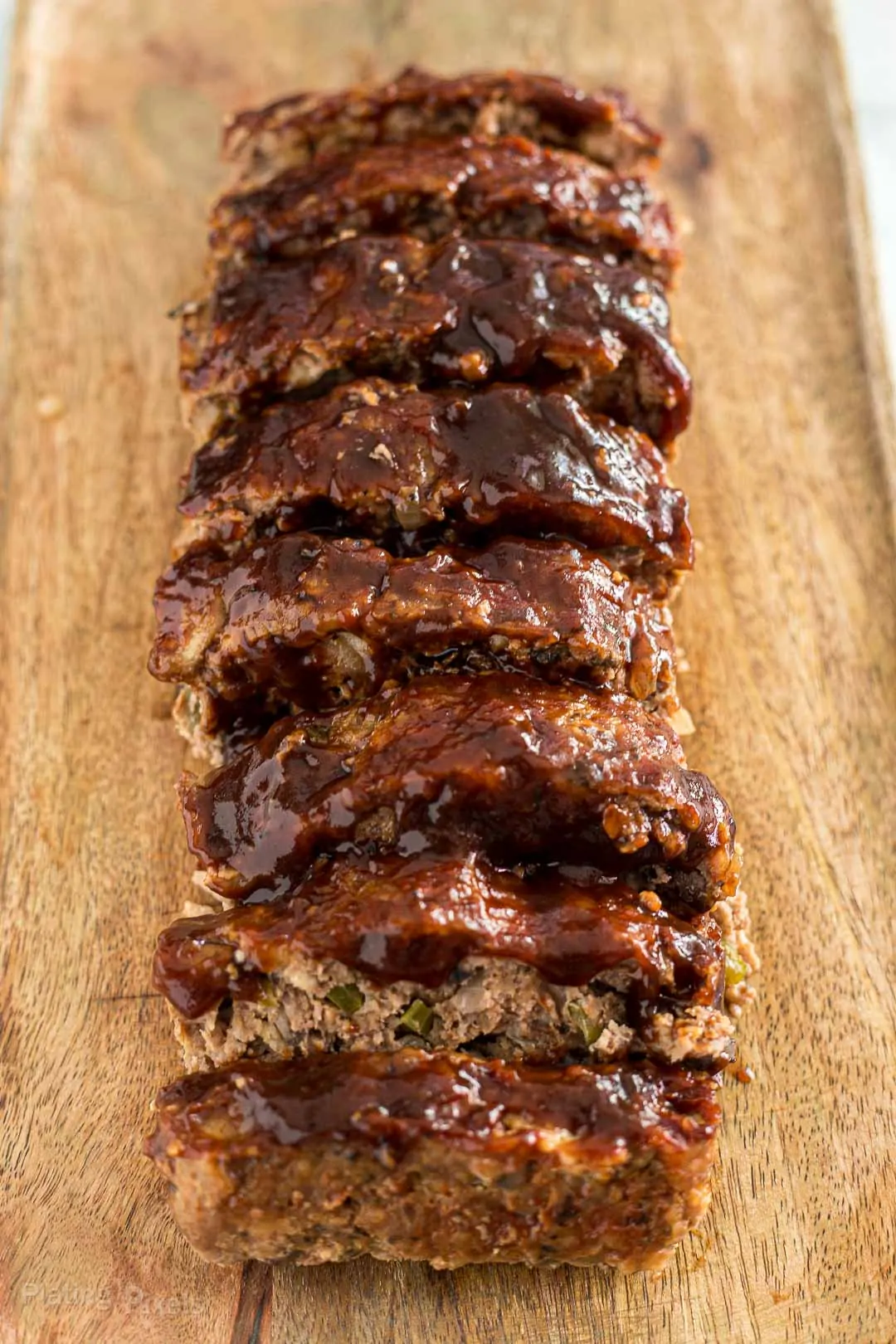 Slices of mushroom meatloaf covered in BBQ sauce on a cutting board