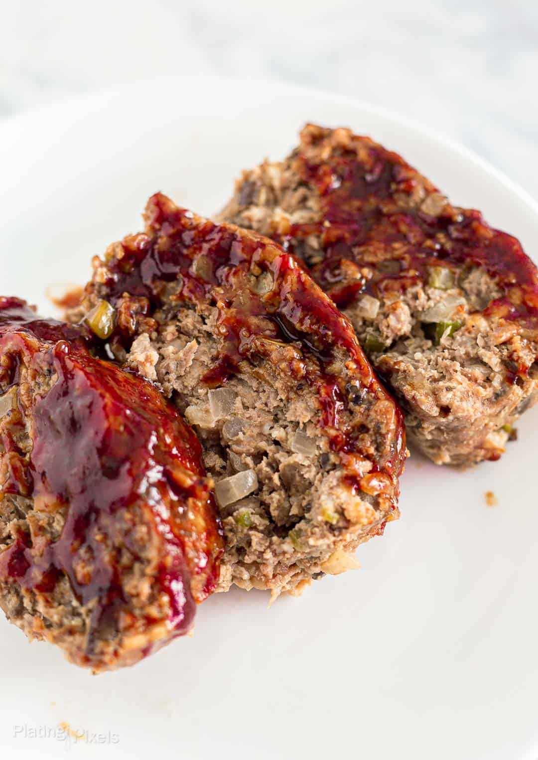 Three slices of meatloaf served on a white plate