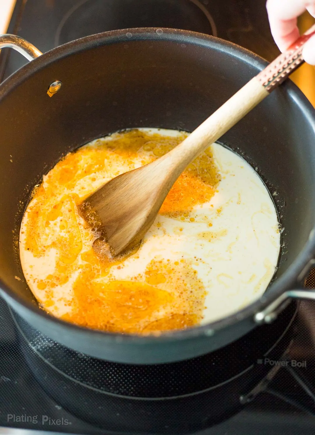 Process shot of adding heavy cream and milk to browned butter in a saucepan